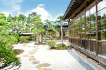 This serene Japanese garden features a traditional wooden house with expansive windows, offering stunning views of the meticulously landscaped grounds.