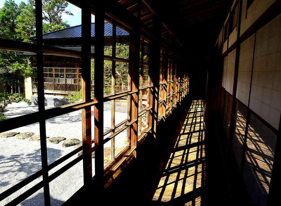 This stunning property features a long corridor with expansive windows offering breathtaking views of a serene Japanese garden.
