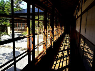 This stunning property features a long corridor with expansive windows offering breathtaking views of a serene Japanese garden.