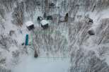 This secluded snowy property features a cluster of cozy cabins nestled amongst a stand of snow-covered trees.