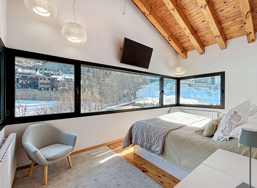 Experience the epitome of comfort and style in this stunning bedroom, featuring expansive windows that frame breathtaking views of a snow-covered landscape.
