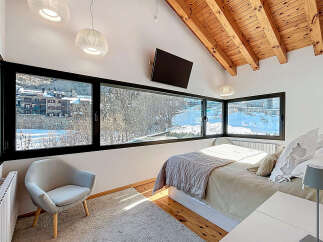 Experience the epitome of comfort and style in this stunning bedroom, featuring expansive windows that frame breathtaking views of a snow-covered landscape.