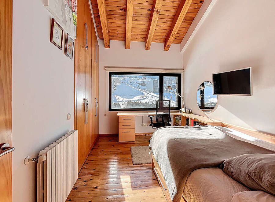This cozy bedroom features a warm wooden ceiling and flooring, creating a comfortable and inviting atmosphere.