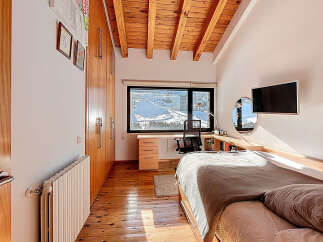 This cozy bedroom features a warm wooden ceiling and flooring, creating a comfortable and inviting atmosphere.
