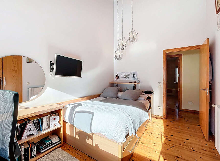 This cozy bedroom features a modern design with a comfortable bed and a mounted TV for entertainment.