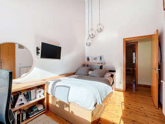 This cozy bedroom features a modern design with a comfortable bed and a mounted TV for entertainment.