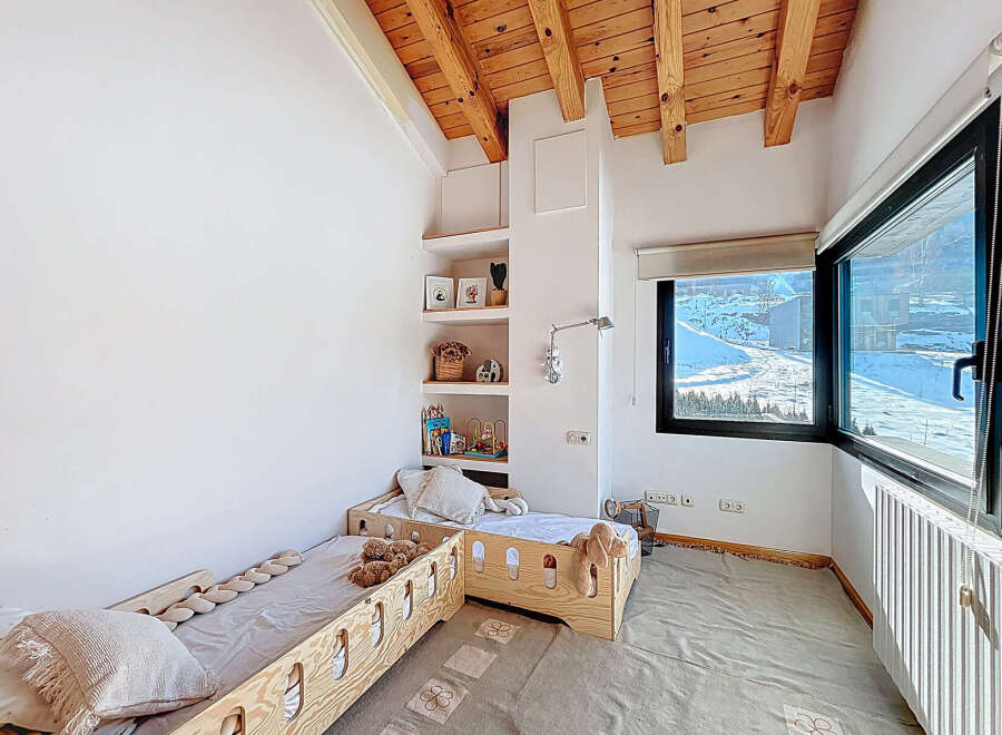 This charming bedroom features a cozy design with wooden accents and a bright, airy feel.