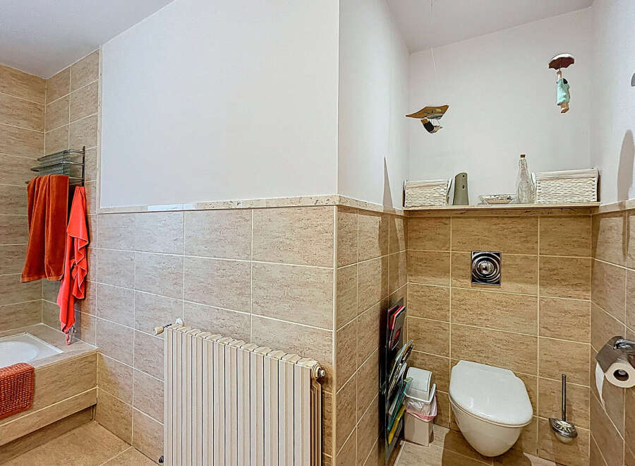 This bathroom features a stylish design with neutral-toned tiles and a modern toilet.