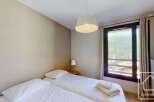 This cozy bedroom features a comfortable double bed, offering stunning mountain views through a large window.
