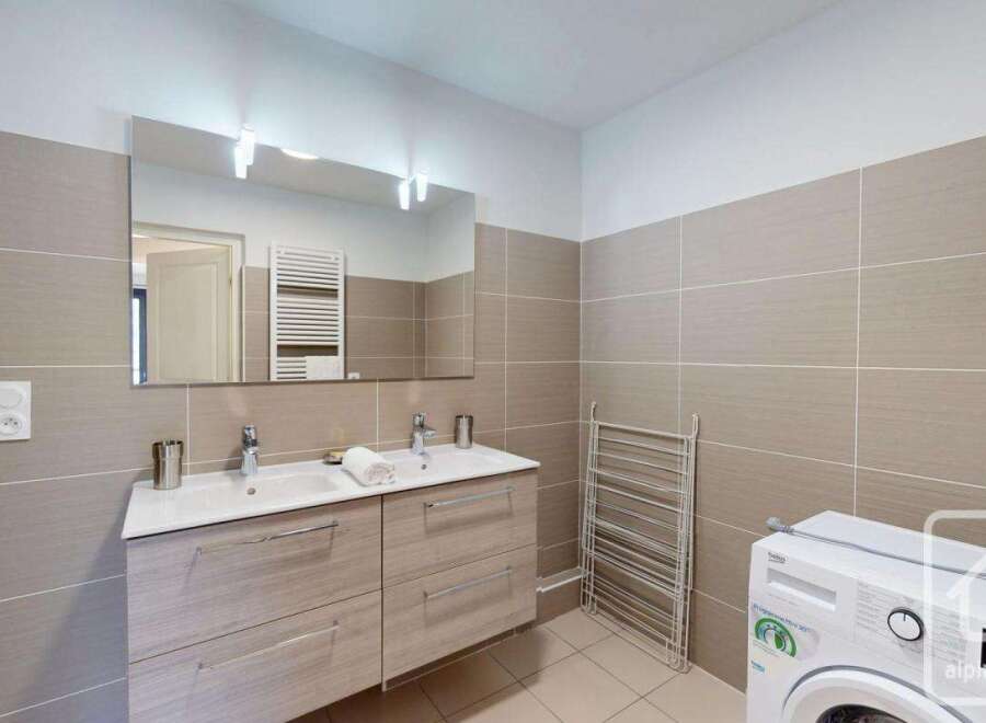 Modern bathroom with double sinks, ample storage, and a convenient washing machine.