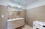 Modern bathroom with double sinks, ample storage, and a convenient washing machine.
