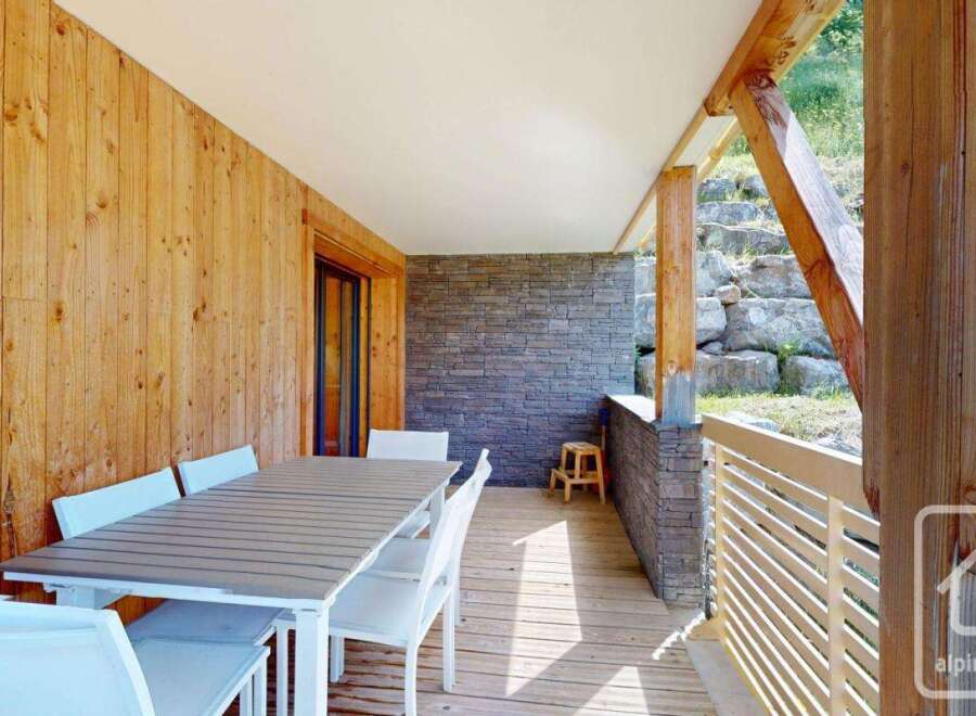 This stunning property boasts a spacious balcony with a wooden deck, perfect for outdoor dining.