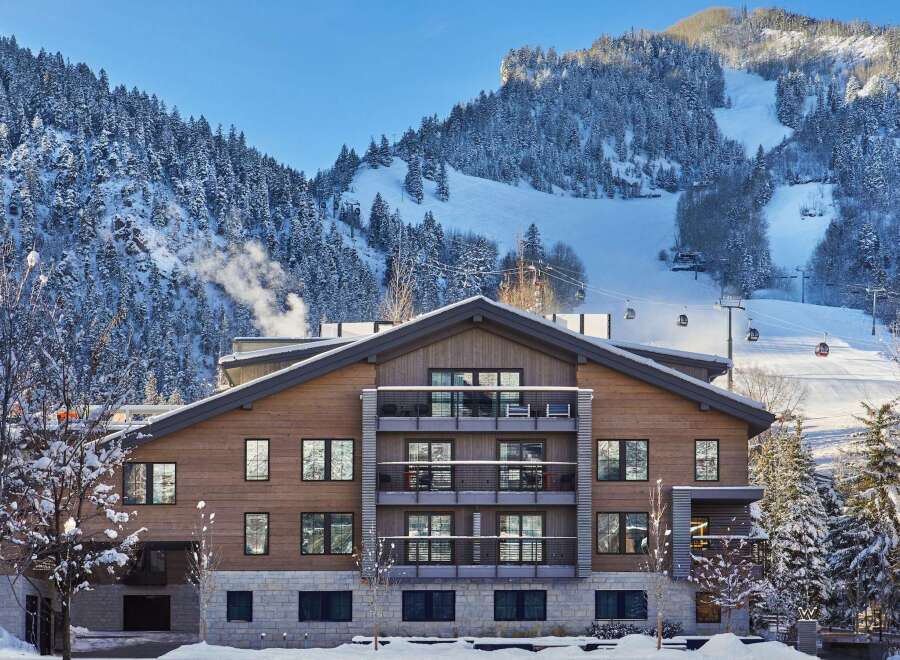 Luxury mountain lodge nestled in a snow-covered landscape, offering stunning views and ski-in/ski-out access.