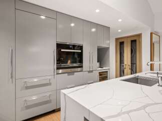 Modern kitchen design with sleek gray cabinetry and a stunning white marble countertop.