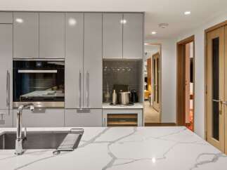This modern kitchen boasts sleek, gray cabinetry and a stunning marble countertop, creating a sophisticated and functional space.
