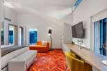 Experience luxury in this stunning bedroom featuring a vibrant orange rug and a stylish chaise lounge.