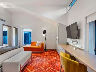 Experience luxury in this stunning bedroom featuring a vibrant orange rug and a stylish chaise lounge.