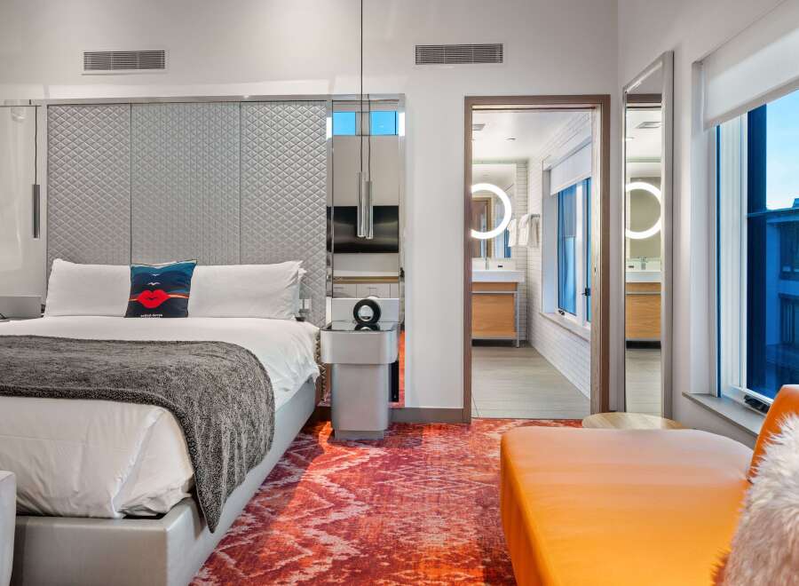 Experience luxury in this stunning hotel room, featuring a plush king-size bed and a vibrant, patterned rug.