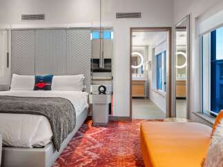 Experience luxury in this stunning hotel room, featuring a plush king-size bed and a vibrant, patterned rug.
