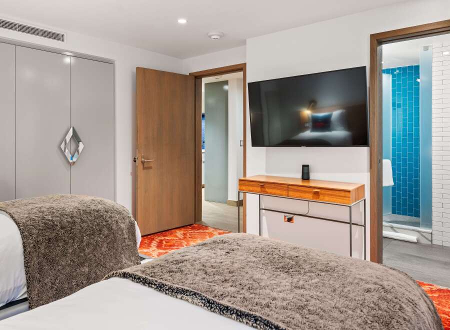 Discover a stylish bedroom featuring a modern design with a sleek TV and a chic wooden console.