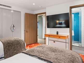 Discover a stylish bedroom featuring a modern design with a sleek TV and a chic wooden console.