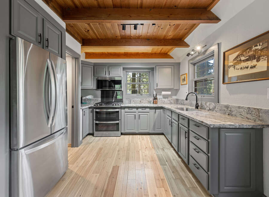 This charming kitchen boasts a rustic-chic design with knotty pine ceilings and exposed beams.