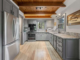 This charming kitchen boasts a rustic-chic design with knotty pine ceilings and exposed beams.