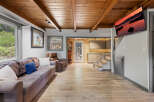 This stunning cabin boasts a spacious living area with hardwood floors, a cozy sofa, and a wood-beamed ceiling.