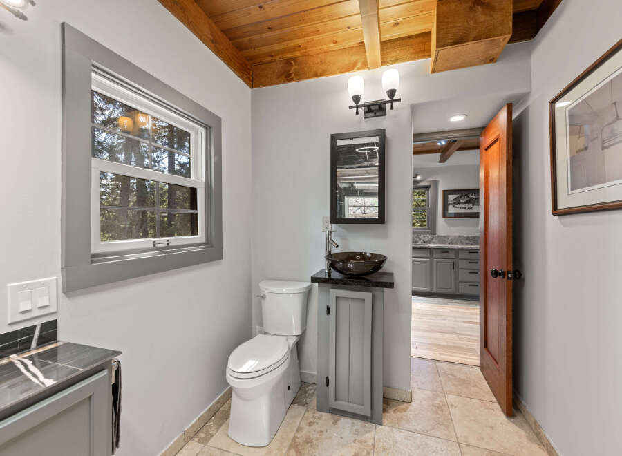 This charming bathroom boasts a modern design with a sleek, dark sink and gray vanity.