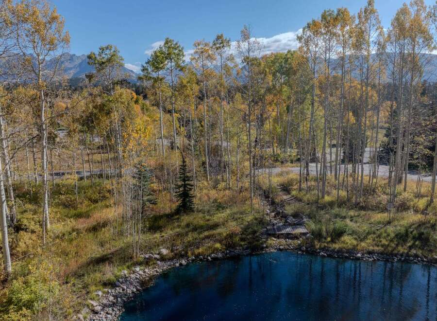 Discover the tranquility of this stunning property, featuring a serene lake surrounded by vibrant autumn foliage.
