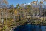 Discover the tranquility of this stunning property, featuring a serene lake surrounded by vibrant autumn foliage.