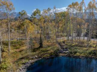 Discover the tranquility of this stunning property, featuring a serene lake surrounded by vibrant autumn foliage.