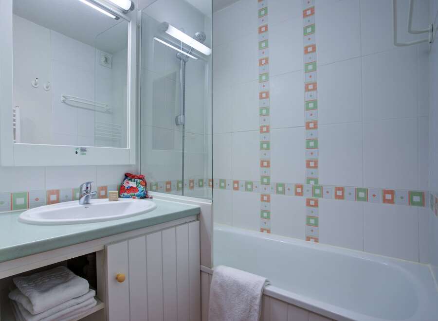 This charming bathroom boasts a clean and modern design, featuring a bathtub, shower, and sink with ample storage space.