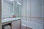 This charming bathroom boasts a clean and modern design, featuring a bathtub, shower, and sink with ample storage space.