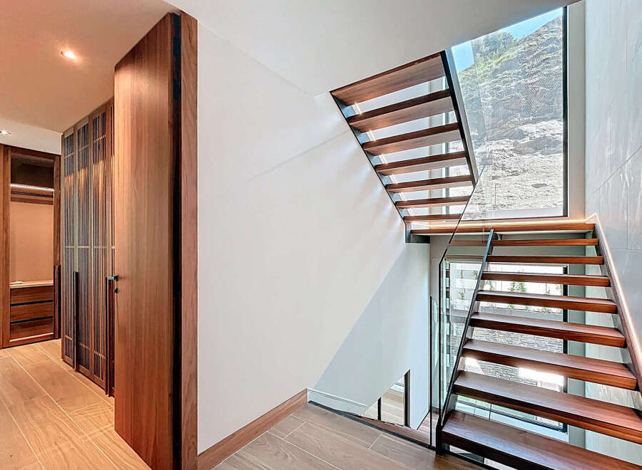 This stunning property boasts a modern staircase with sleek wooden steps and a glass railing, creating a seamless flow.