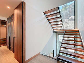 This stunning property boasts a modern staircase with sleek wooden steps and a glass railing, creating a seamless flow.