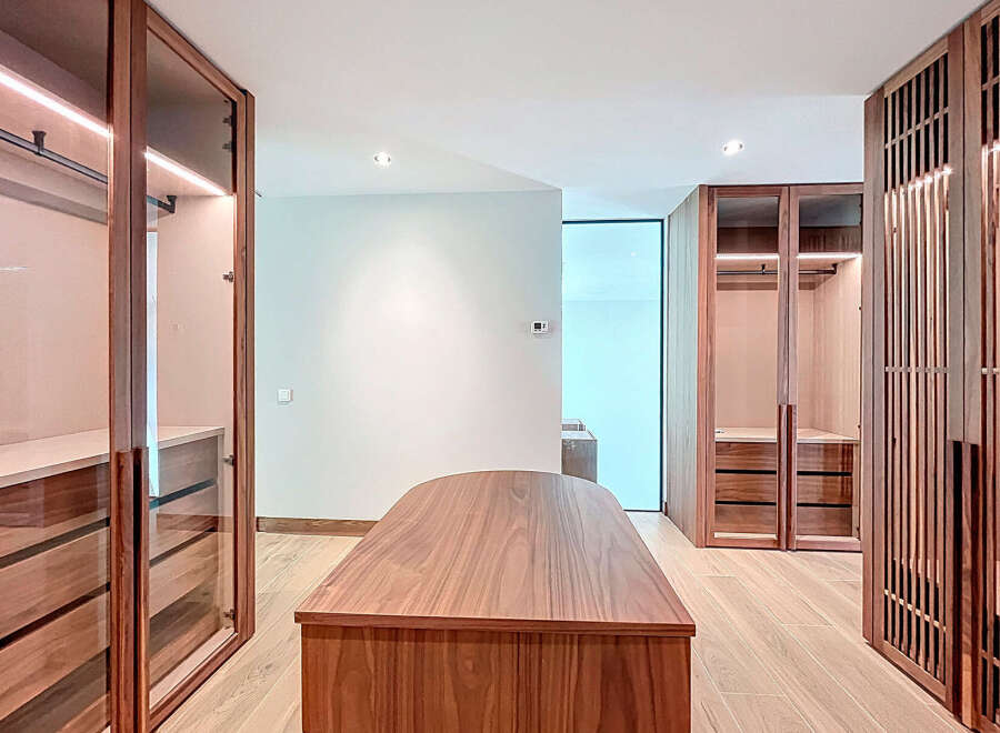 Step into luxury with this stunning walk-in closet, featuring custom wood cabinetry and ample storage space.