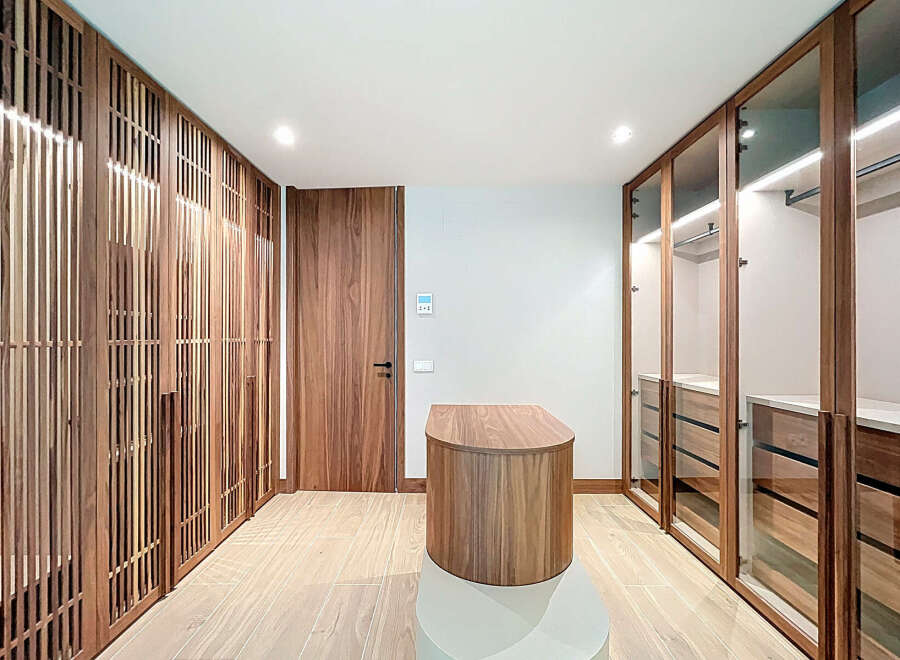 Step into luxury with this stunning walk-in closet, featuring custom wood cabinetry and ample storage space.