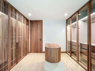 Step into luxury with this stunning walk-in closet, featuring custom wood cabinetry and ample storage space.