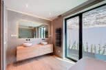 This modern bathroom boasts a sleek design with a floating wooden vanity and two stylish vessel sinks.