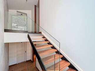 Discover the elegance of this modern staircase, featuring sleek glass railings and warm wooden steps.