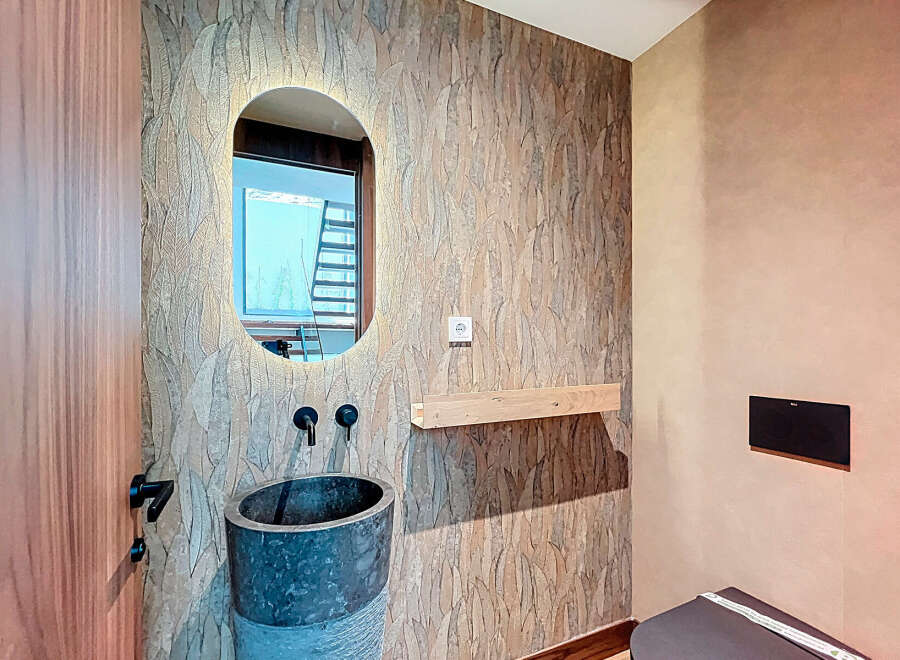 This stunning bathroom boasts a unique design with a textured accent wall and a modern oval mirror.