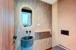 This stunning bathroom boasts a unique design with a textured accent wall and a modern oval mirror.