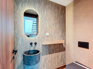 This stunning bathroom boasts a unique design with a textured accent wall and a modern oval mirror.