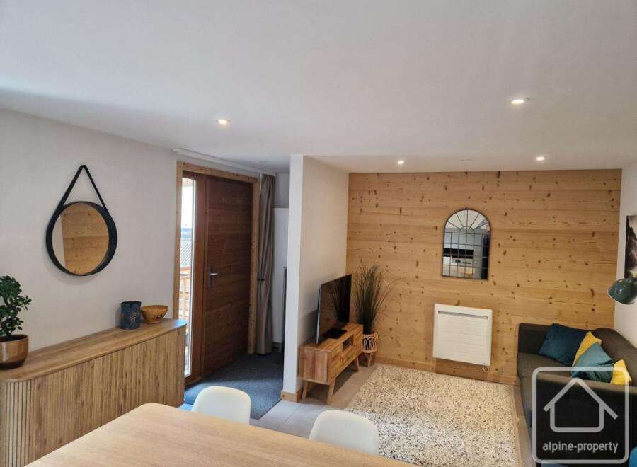 Discover this charming property featuring a cozy living space with a wooden accent wall and a comfortable sofa.