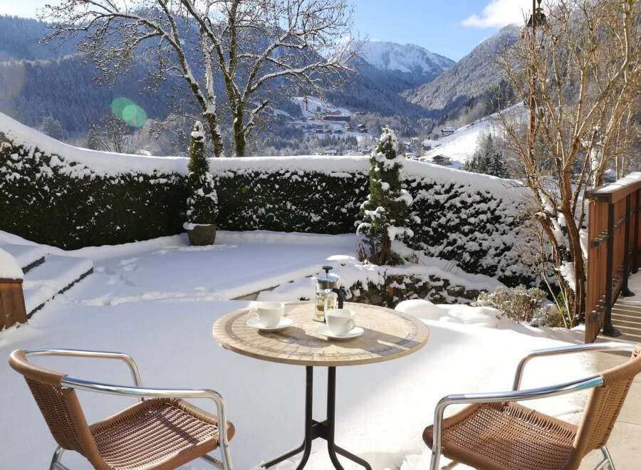 Enjoy the serene beauty of this snow-covered property with a charming outdoor seating area.