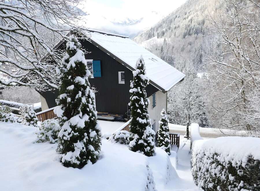 Nestled in a serene winter wonderland, this charming property boasts a snow-covered roof and lush evergreen trees.