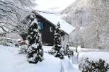 Nestled in a serene winter wonderland, this charming property boasts a snow-covered roof and lush evergreen trees.
