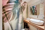 This stunning bathroom features a unique monstera leaf wallpaper, creating a serene and natural ambiance.
