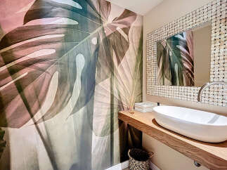 This stunning bathroom features a unique monstera leaf wallpaper, creating a serene and natural ambiance.